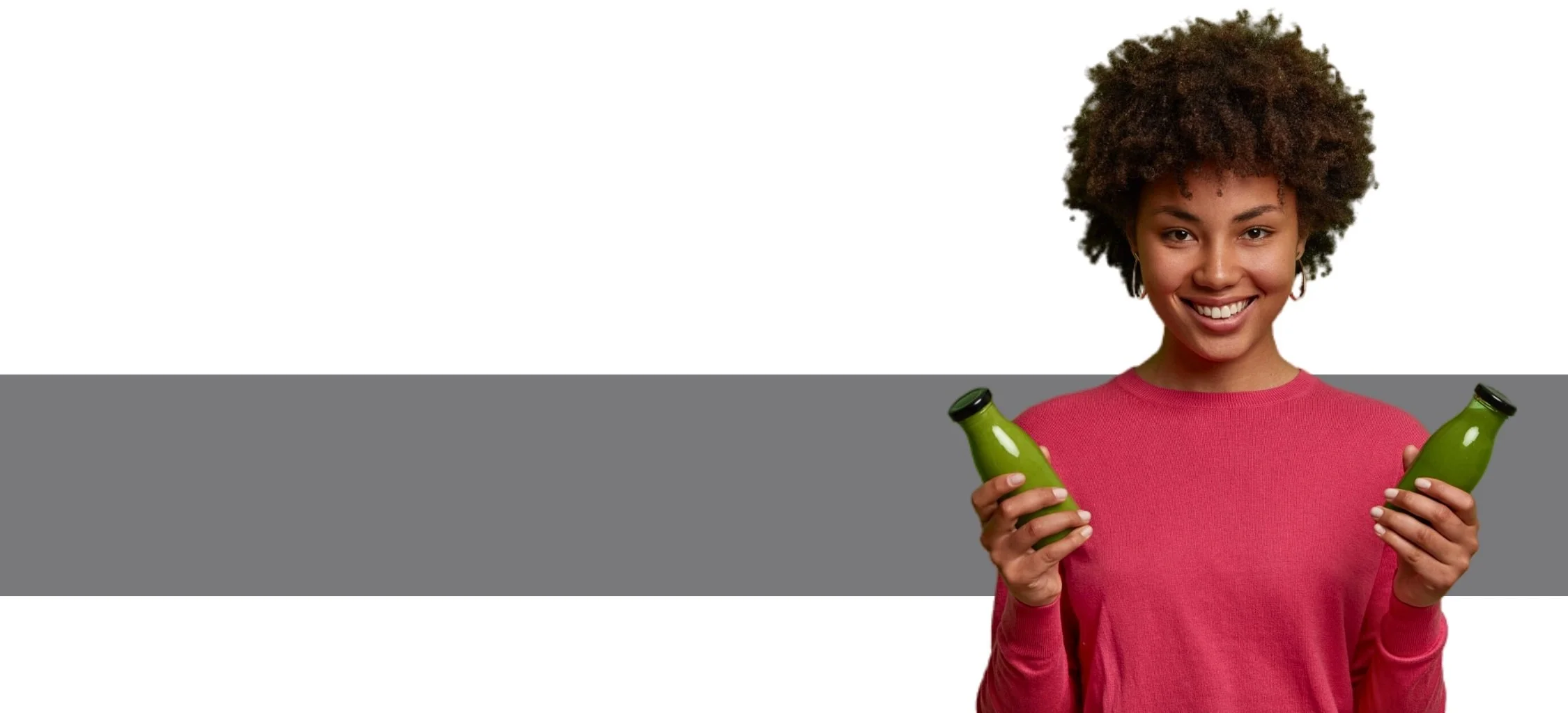 Person holding green smoothies, wearing a pink sweater